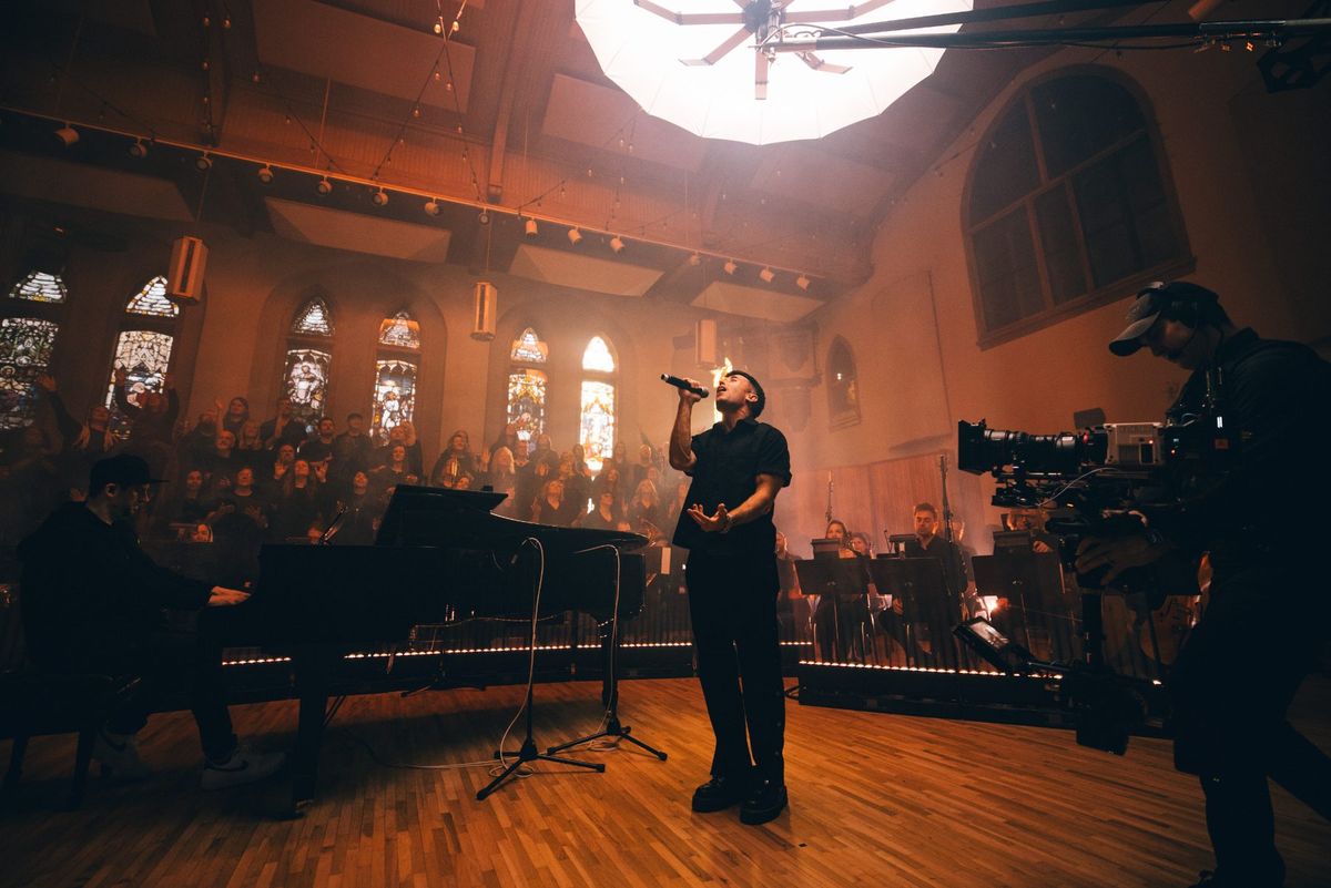 Camera operator framing a singer at the edge of the stage during a Tommee Profitt live recording